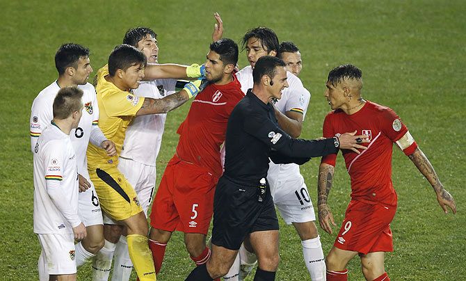 Peru and Bolivia players argue as referee Wilmar Roldan attempts to restrain them