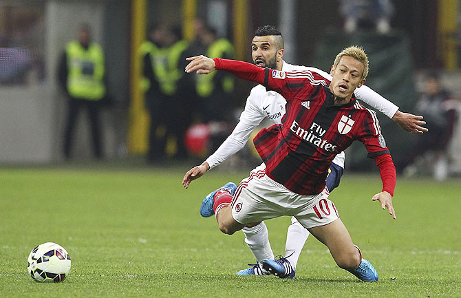 Keisuke Honda of AC Milan is challenged by Mounir Obbadi of Hellas Verona FC during the Serie A match at Stadio Giuseppe Meazza in Milan on Saturday