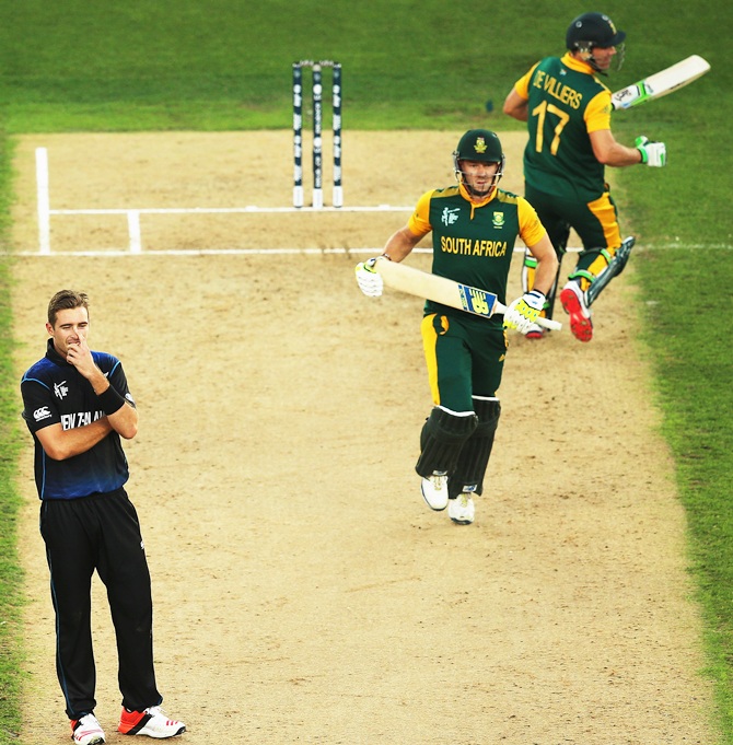 Tim Southee of New Zealand looks on as David Miller of South Africa and AB de Villiers of cross for a run
