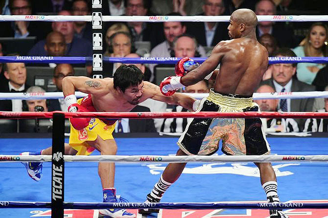 Manny Pacquiao lands a punch against Floyd Mayweather, Jr. (right)