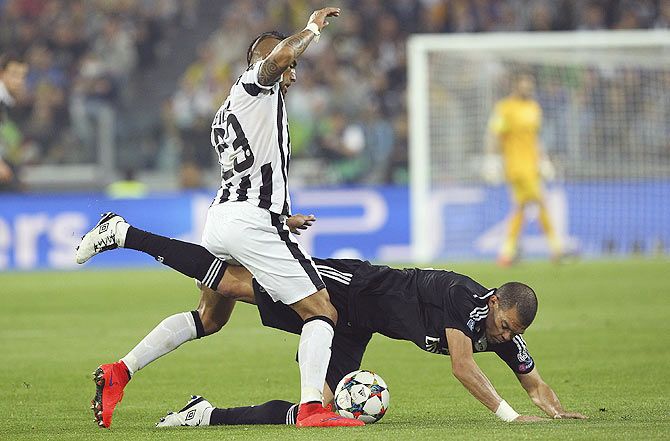 Pepe (bottom) of Real Madrid CF is challenged by with Arturo Vidal (L) of Juventus FC