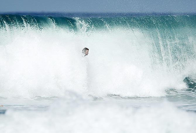 A large wave breaks onto a surfer as he tries to drop in for a ride in Cardiff, California, on May 4