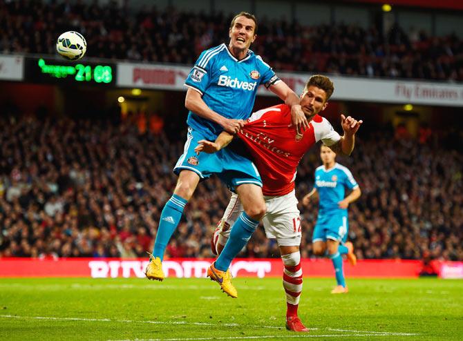 John O'Shea of Sunderland and Olivier Giroud of Arsenal tussle for the ball during their English Premier League match at Emirates Stadium in London on Wednesday