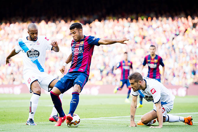 FC Barcelona's Rafinha (centre) controls the ball between Sidnei (left) and Alberto Lopo (right) of RC Deportivo La Coruna