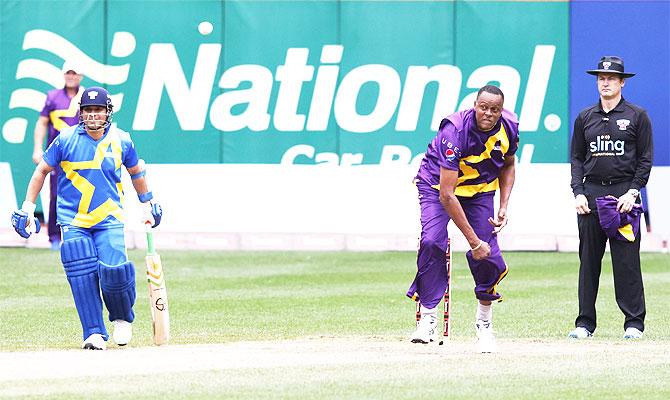 West Indian legend Courtney Walsh bowls as Sachin Tendulkar looks on