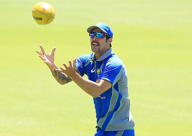 Mitchell Johnson marks a football as players warm up during an Australian nets session 