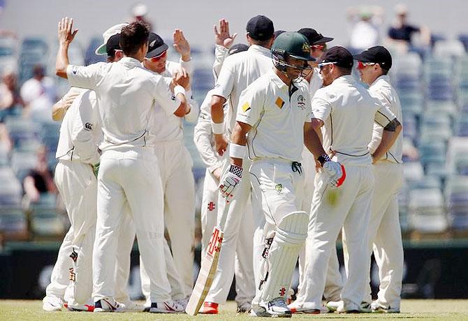 Members of the New Zealand team celebrate after dismissing Australia's David Warner (centre)