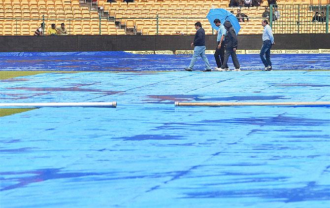 Ground incharge with Fourth Umpire walks on the field, as the 4th day's play of the 2nd Test between India and South Africa was called off due to rains at the Chinnaswamy Stadium in Bengaluru on Tuesday