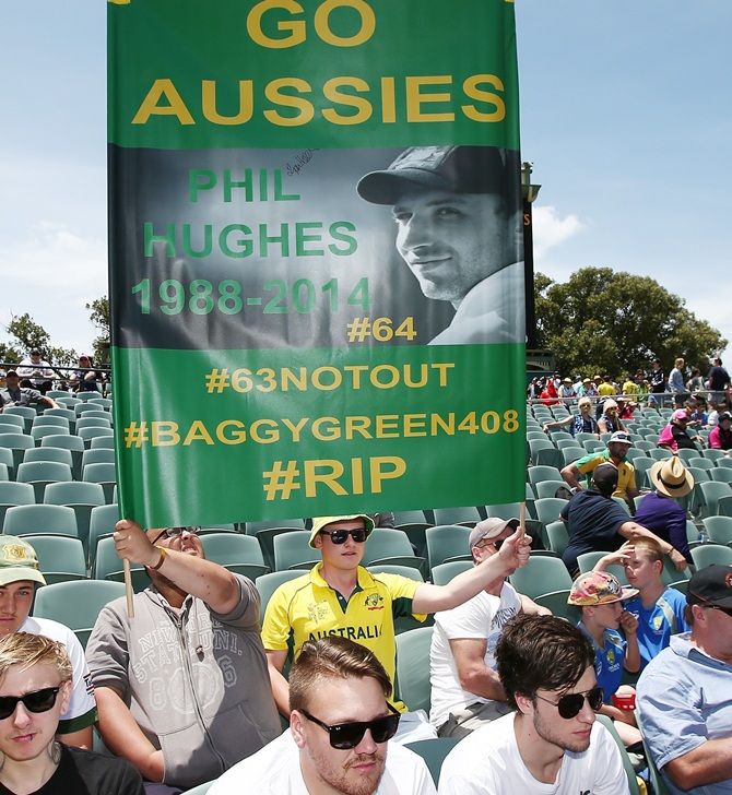 Spectators hold up a tribute to former cricketer Phillip Hughes