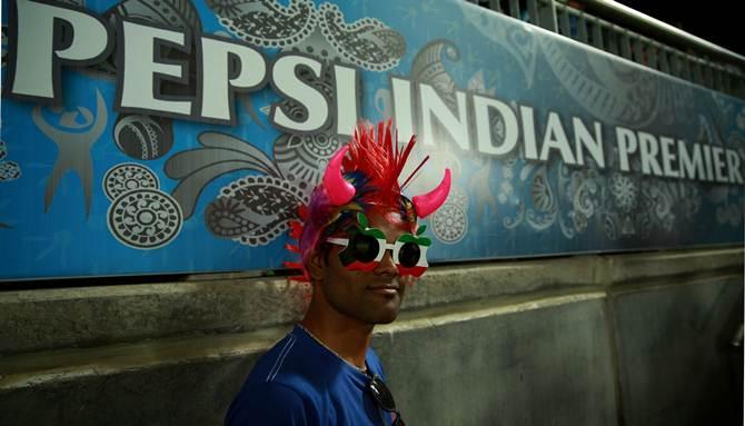 A fan poses in fron of a banner of the main IPL sponsor