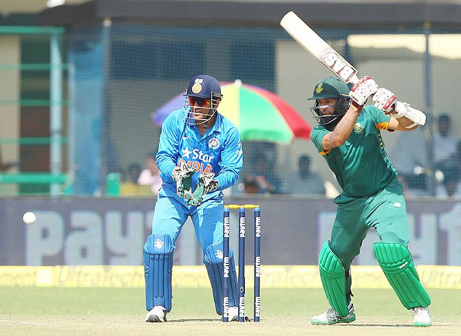 Hashim Amla plays a shot on the off-side as Mahendra Singh Dhoni looks on
