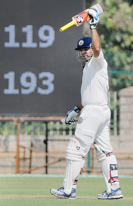 Virender Sehwag celebrating raises his bat after scoring a century in Ranaji Trophy against Karnataka in Mysore on Thursday