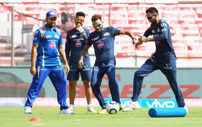 Mumbai Indians' Rohit Sharma watches teammates Hardik Pandya and Krunal Pandya involved in a football match during a training session