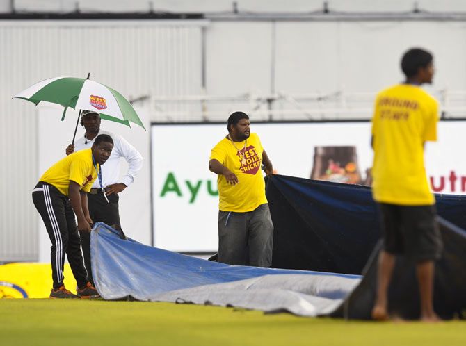 Groundstaff work on the covers at the Queens Park Oval in Port of Spain, Trinidad