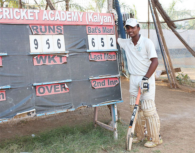 Pranav Dhanawade stands proudly beside the scoreboard at the end of Day 1 