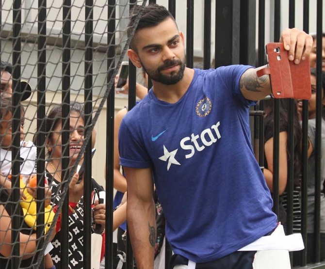 India's Virat Kohli poses for a selfie with fans 