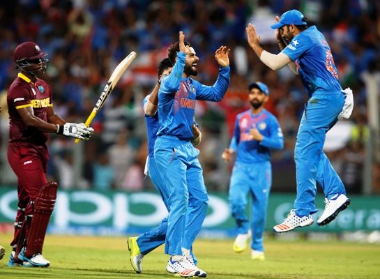 India's Virat Kohli (centre) celebrates with his teammates after taking the wicket of West Indies Johnson Charles