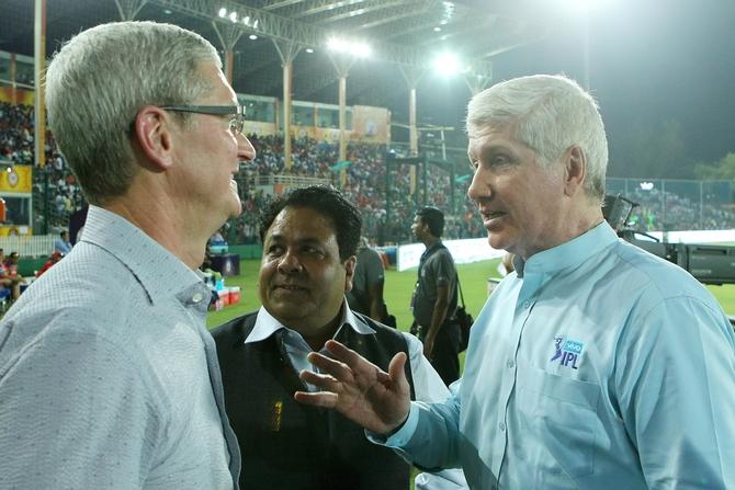 Alan Wilkins, right, speaks with Apple CEO Tim Cook, left, as IPL Chairman Rajeev Shukla looks on at an IPL game in 2016