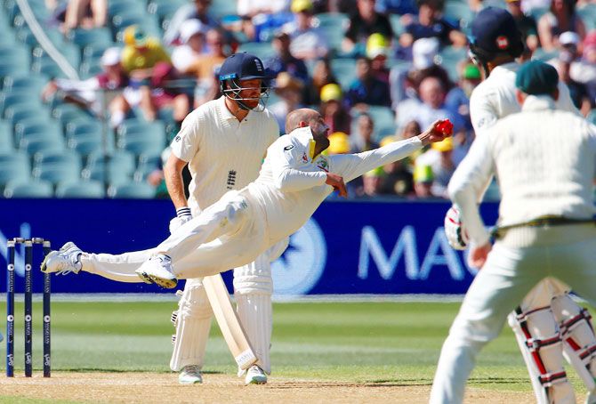 Australia's Nathan Lyon dives full length as he completes a catch to dismiss England's Moeen Ali during the third day of the second Ashes cricket Test match at the Adelaide Oval in Adelaide on Monday
