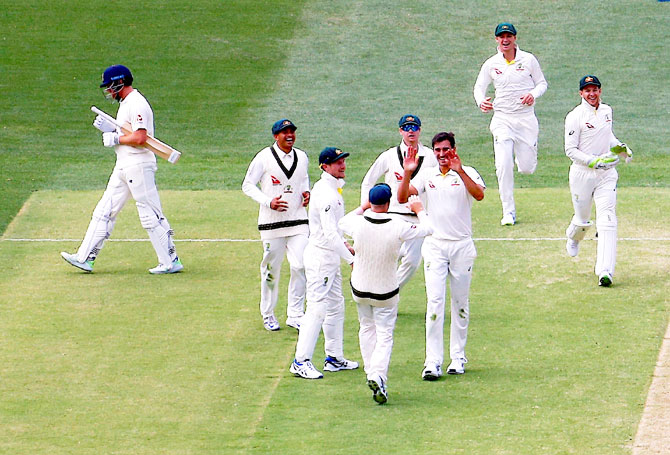 England's Jonny Bairstow walks off the ground as Australia's Mitchell Starc celebrates with teammates after taking a catch to dismiss him on Monday