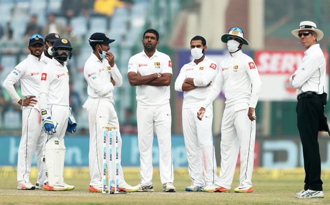 Face mask-donning Sri Lankan players wait for a DRS review on Day 4 of the 3rd Test in New Delhi on Tuesday
