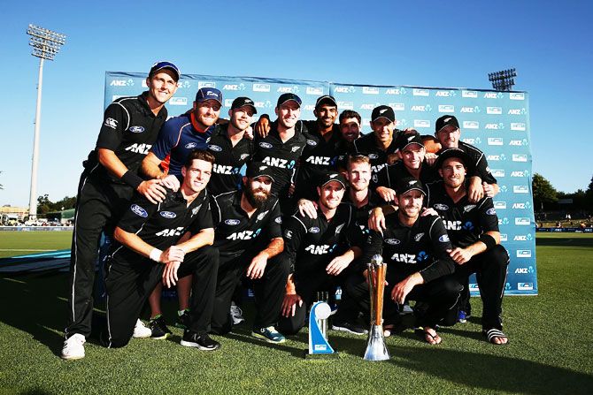 New Zealand players pose for cameras as they celebrate with the Chappell-Hadlee Trophy and the ANZ Series Trophy after winning game three of the One-Day International series against Australia at Seddon Park in Hamilton on Sunday