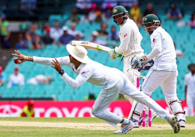 Australia's Usman Khawaja watches as Pakistan's Younis Khan dives to field the ball