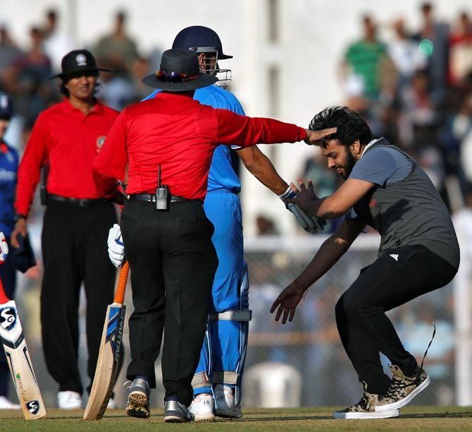 A fan invades the pitch as he tries to touch the feet of India 'A' captain M S Dhoni (2nd from right) during the first warm up match against England at the Brabourne Stadium in Mumbai on Tuesday