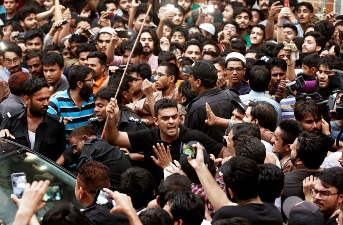 A local policeman uses a baton to disperse cricket fans gathered outside Sarfraz Ahmed's house in celebration of the Champion Trophy win