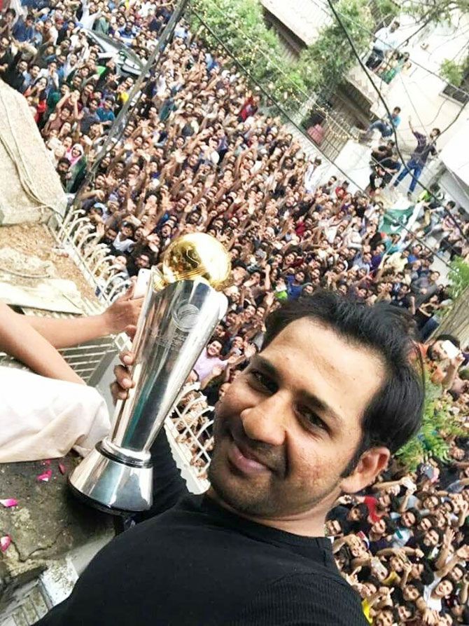 Pakistan captain Sarfraz Ahmed's home is surrounded by fans as he shows off the Champions Trophy from the balcony of his home