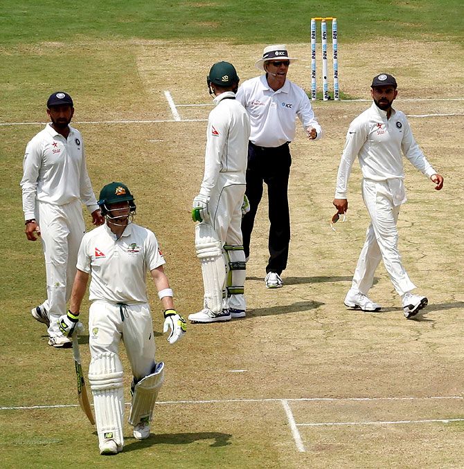 India captain Virat Kohli, right, speaks to the umpire as Steve Smith walks back after his dismissal