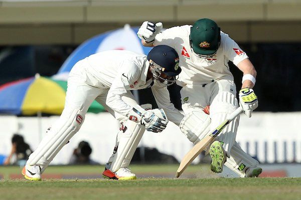 India 'keeper Wriddhiman Saha gets into an awkward position as he tries to get the ball from between Steve Smith's legs