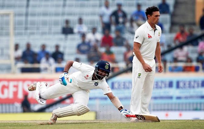 India's Cheteshwar Pujara dives to avoid being run out as Australia's Steve O'Keefe (R) looks on in despair