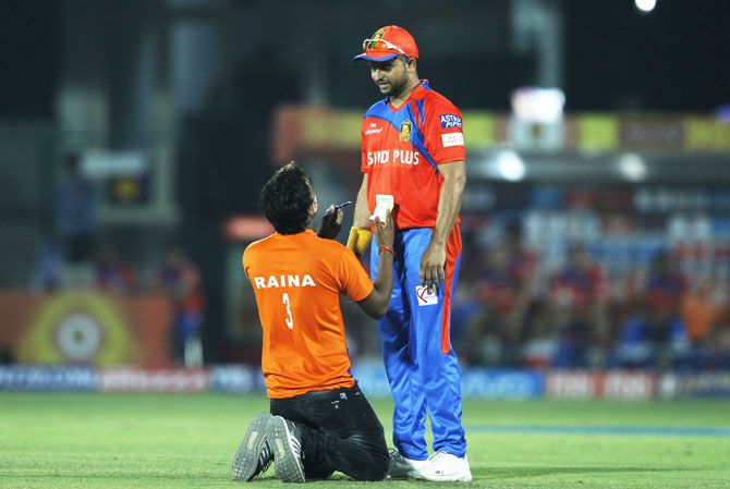 A spectator breaks the security cordon, runs on to the field to ask Gujarat Lions captain Suresh Raina for an autograph