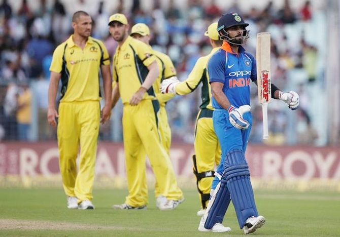 Australia's players celebrate as India captain Virat Kohli walks back after being dismissed