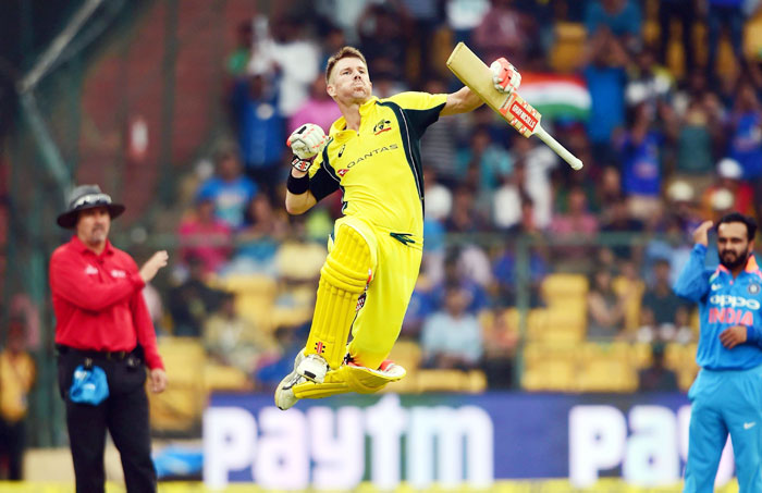 Australia's David Warner celebrates in his signature style after completing his century at the Chinnaswamy Stadium in Bengaluru on Thursday