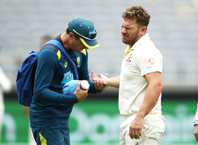 Aaron Finch reacts as he gets treatment from Australian Team Physiotherapist David Beakley after being struck on the hand by a delivery from Ishant Sharma