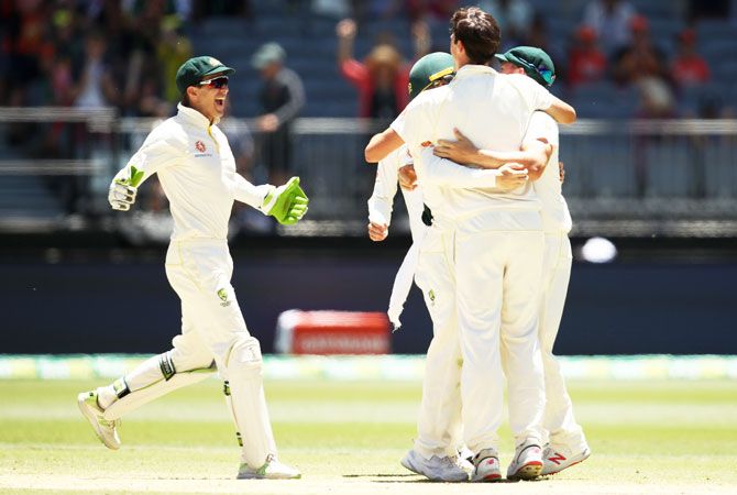Australia captain Tim Paine runs in to celebrate with teammates after winning the second Test against India at Perth Stadium in Perth on Tuesday