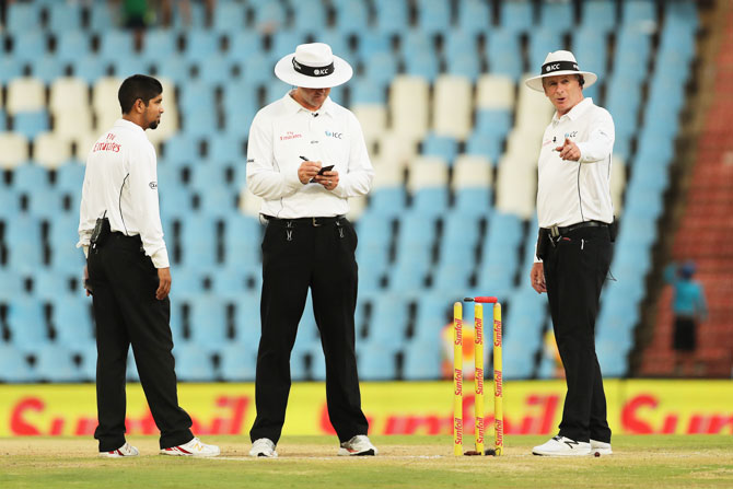 The umpires place the light meter on the stumps for a reading and check the light 