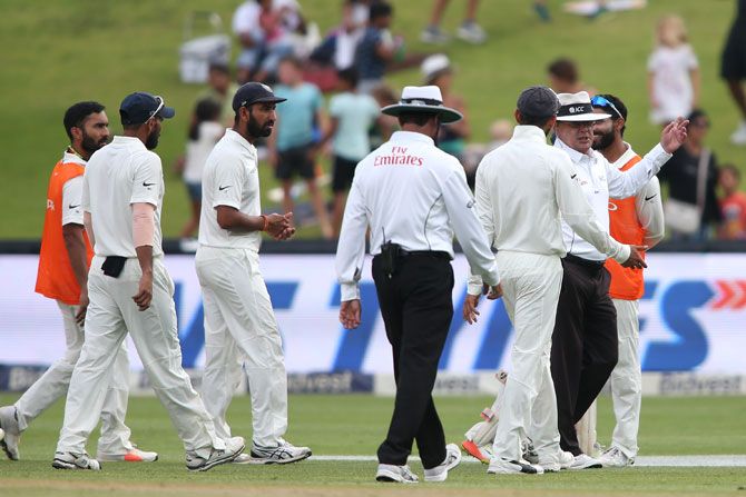Virat Kohli chats with umpires Ian Gould and Aleem Dar as they lead the players off the field