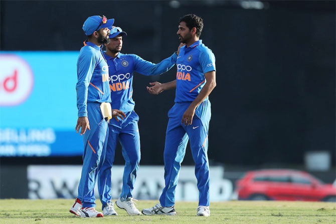 Bhuvneshwar Kumar celebrates with captain Kohli and Kuldeep Yadav after taking a diving catch on his follow-up to dismiss Roston Chase 