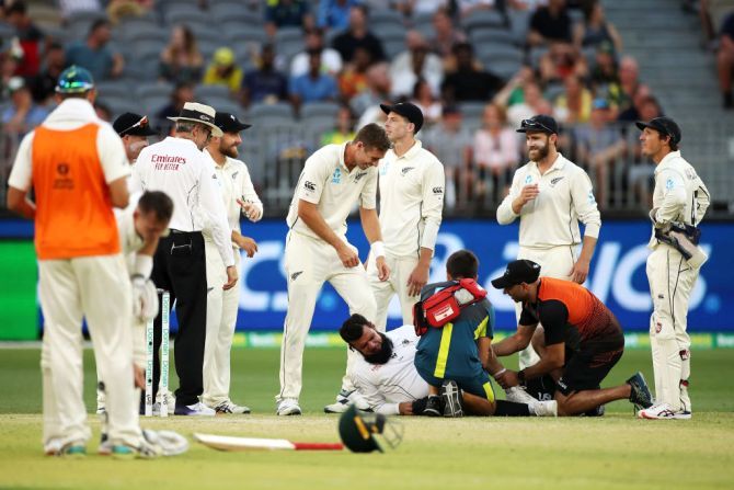 Umpire Aleem Dar receives attention after he collided with New Zealand's Mitchell Santner