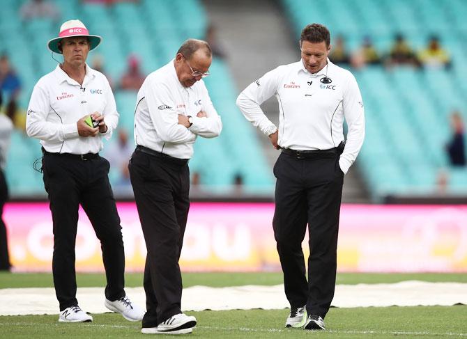 Umpires Ian Gould and Richard Kettleborough ponder as bad light delayed the start of play