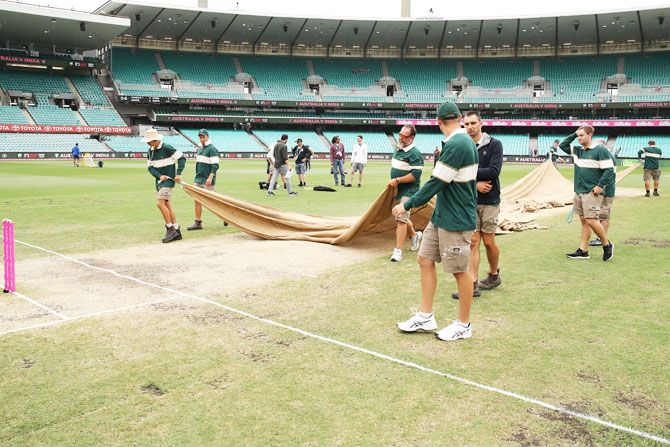 The ground staff cover the pitch before the scheduled start of play on day five of the 4th Test match between Australia and India at Sydney Cricket Ground in Sydney on Monday