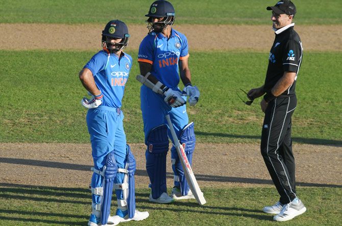 Virat Kohli and Shikhar Dhawan speak to Tim Southee as the players are forced off the field because of sun