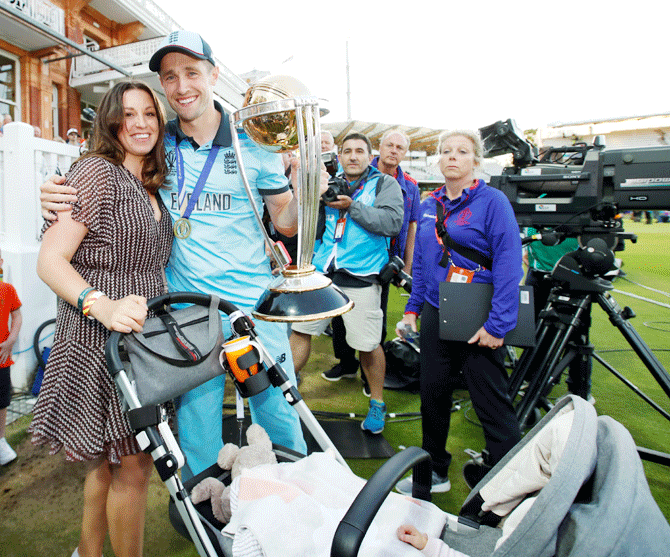 Chris Woakes holds up the trophy as he celebrates with family 