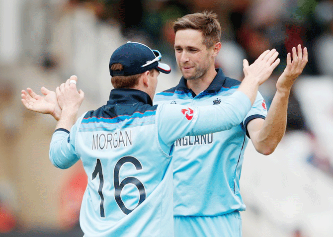 England's Chris Woakes and Eoin Morgan celebrate a wicket