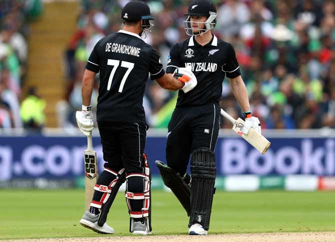 Jimmy Neesham (r) of New Zealand shakes hands with Colin de Grandhomme after reaching his fifty