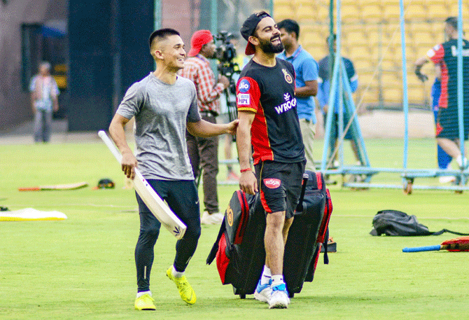 Royal Challengers Bangalore skipper Virat Kohli and India football captain Sunil Chhetri joke about after a practice session at Chinnaswamy Stadium, in Bengaluru on Tuesday