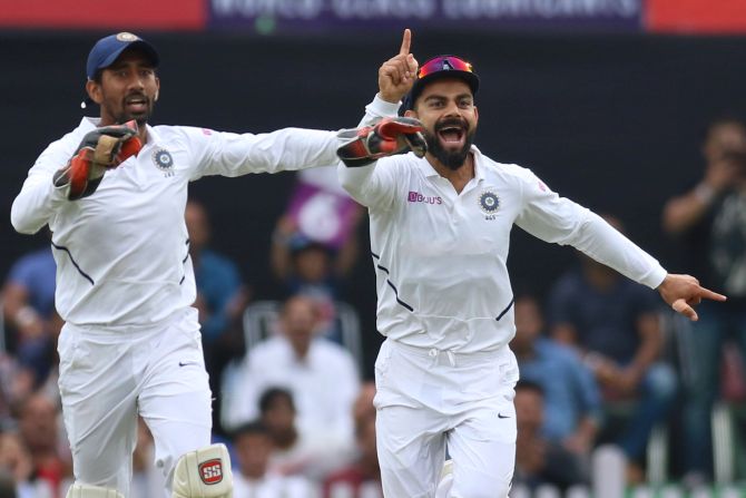 Virat Kohli and Wriddhiman Saha celebrate the wicket of South Africa's Dean Elgar